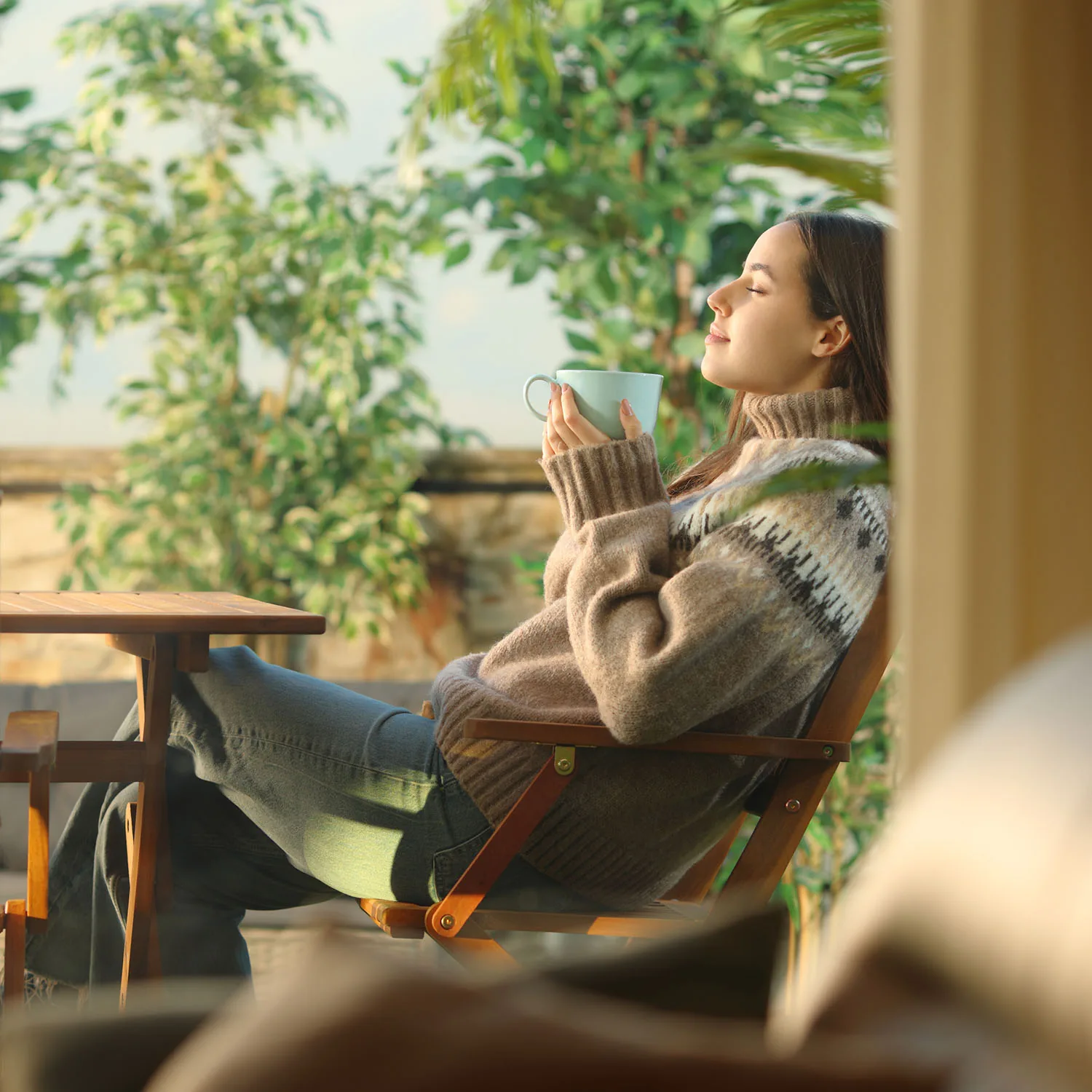 Momentaufnahme einer Frau, die entspannt auf einem Stuhl sitzt und eine Tasse in den Händen hält.