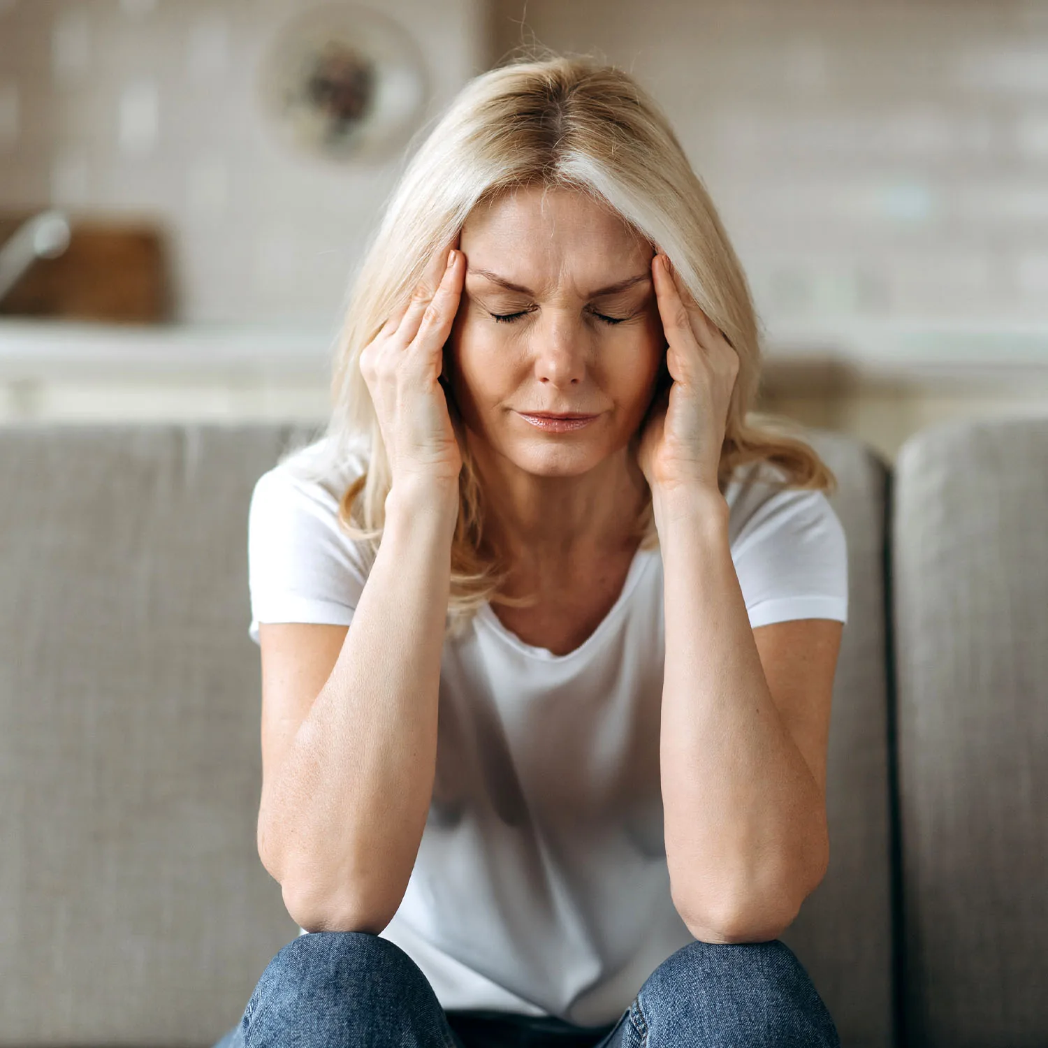 Eine Frau hält sich den Kopf und hat einen schmerzhaften Gesichtsausdruck.