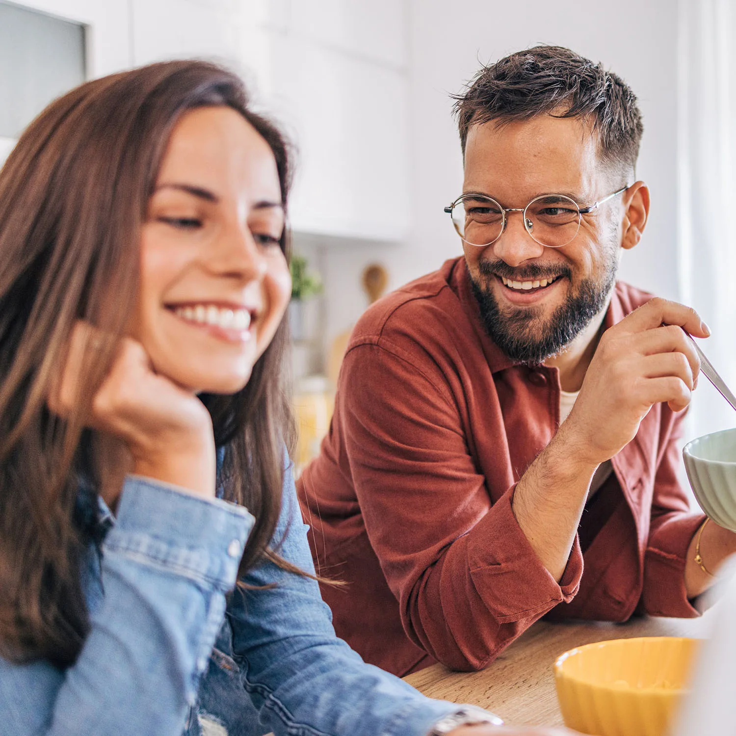 Zwei Personen, die fröhlich nebeneinander am Tisch sitzen.
